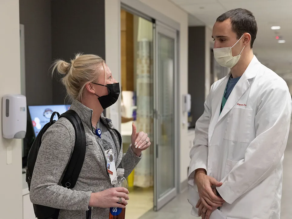 Aaron Craft talks to a nurse in a hallway of the Wexner Medical Center